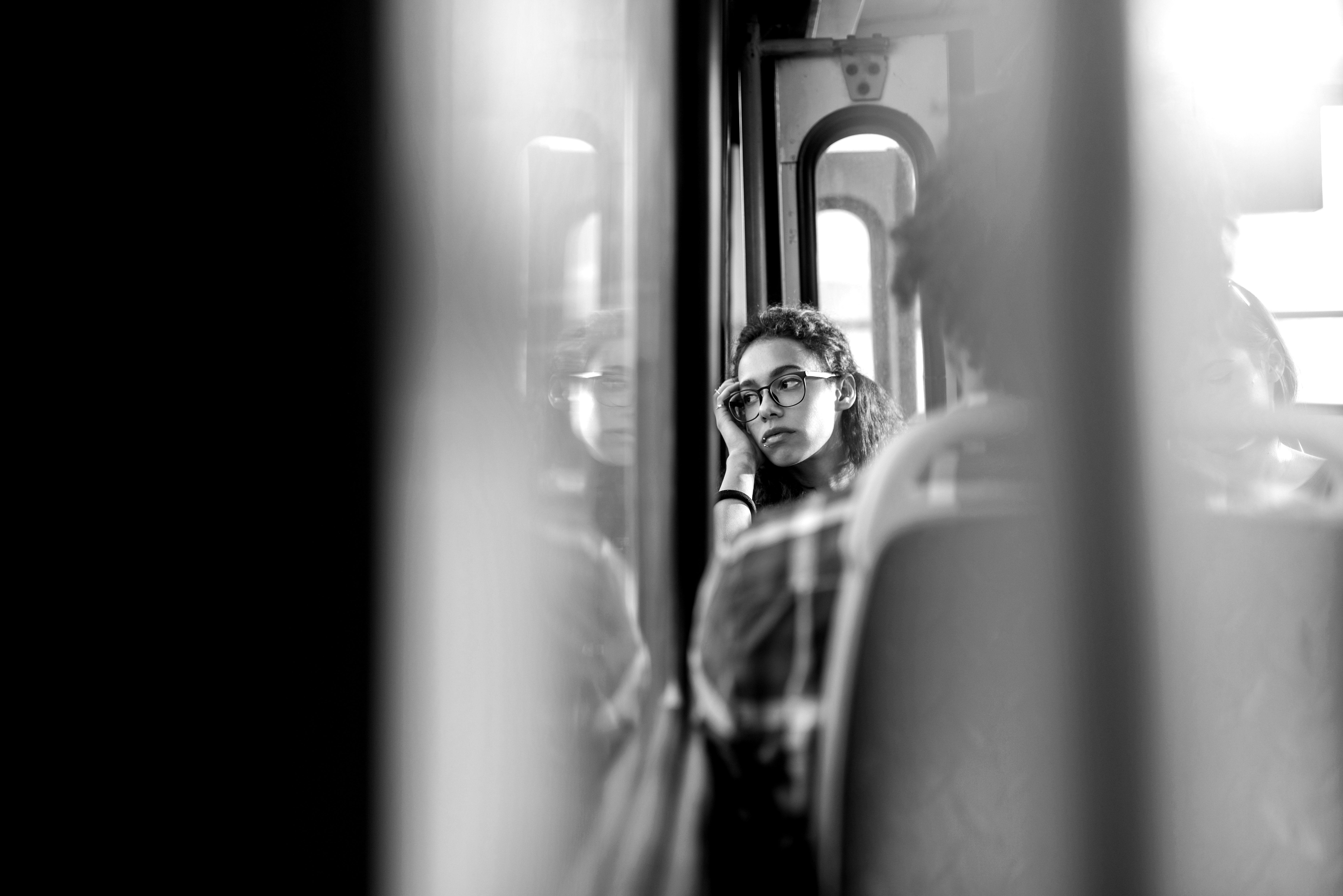 A woman rests her head on her hand, looking out of the window on public transport.